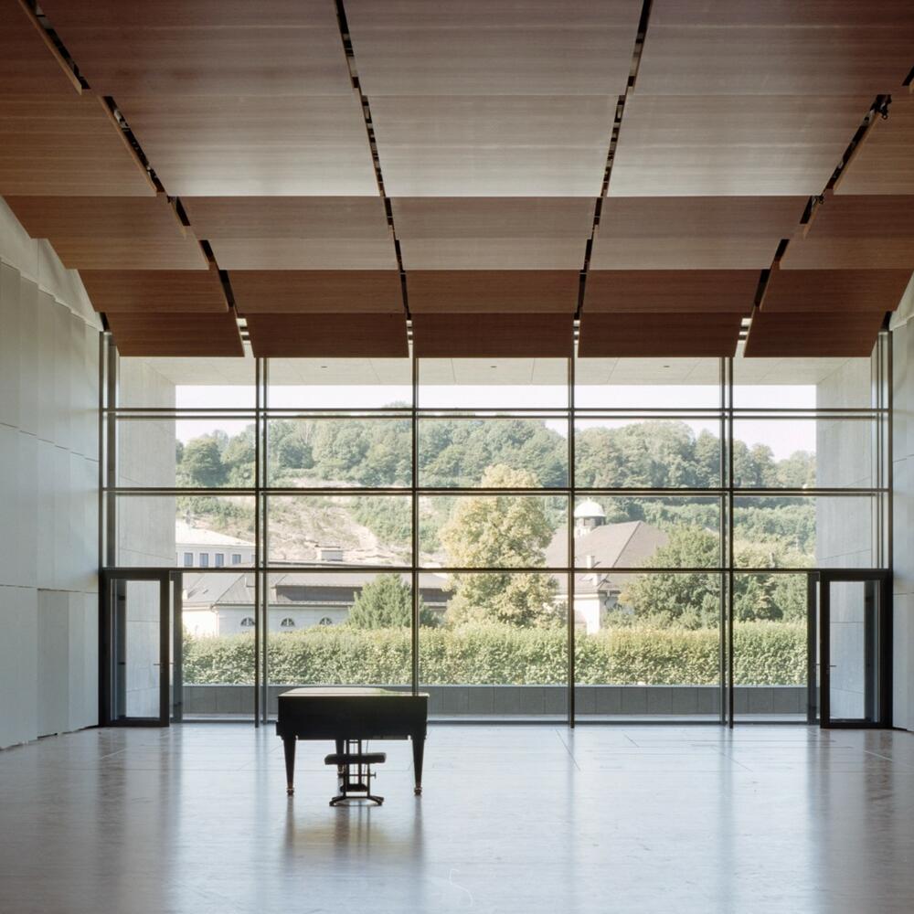 Leerer Solitär, Parkettboden, große Fensterfront, davor ein Piano | © Andrew Phelps