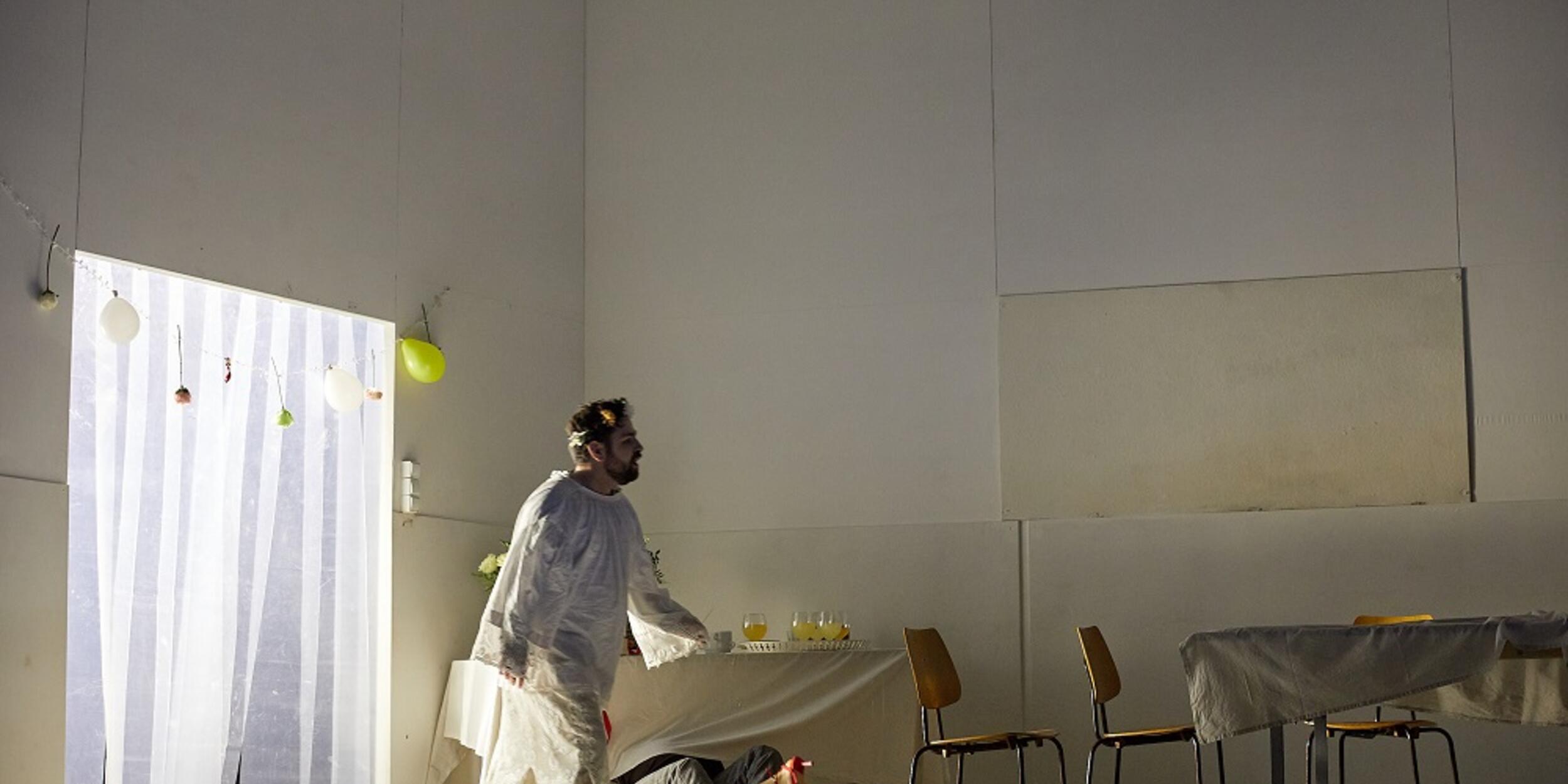 Mann in weißer Schutzkleidung geht über eine Bühne | © Judith Buss